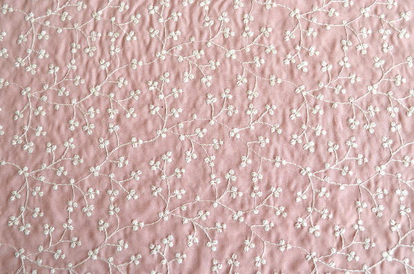 Stof geborduurd gebroken wit op roze, kleine bloem